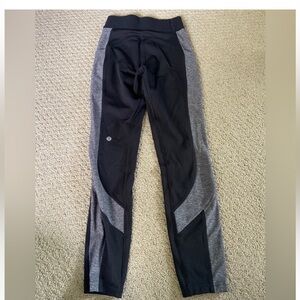 Black Lululemon leggings with gray side panel.